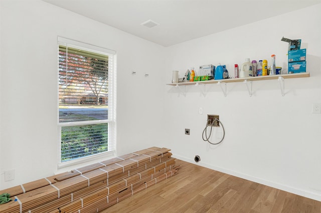 clothes washing area with electric dryer hookup, plenty of natural light, washer hookup, and wood-type flooring