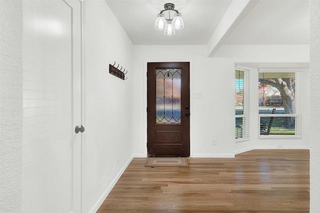 foyer entrance with beamed ceiling, a notable chandelier, and light hardwood / wood-style floors