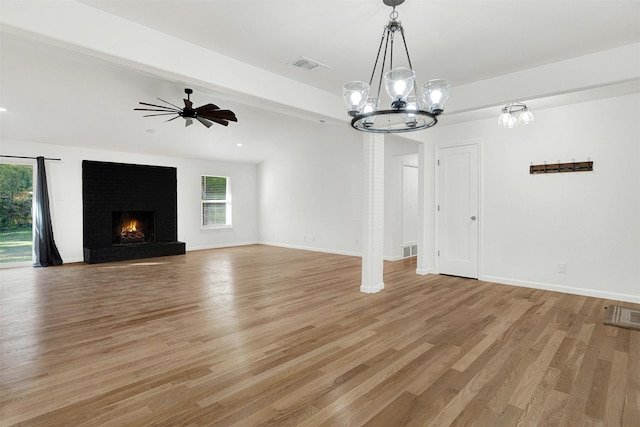 unfurnished living room with hardwood / wood-style floors, ceiling fan with notable chandelier, and a brick fireplace