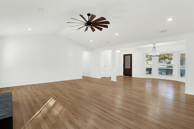 unfurnished living room featuring wood-type flooring, ceiling fan with notable chandelier, and vaulted ceiling