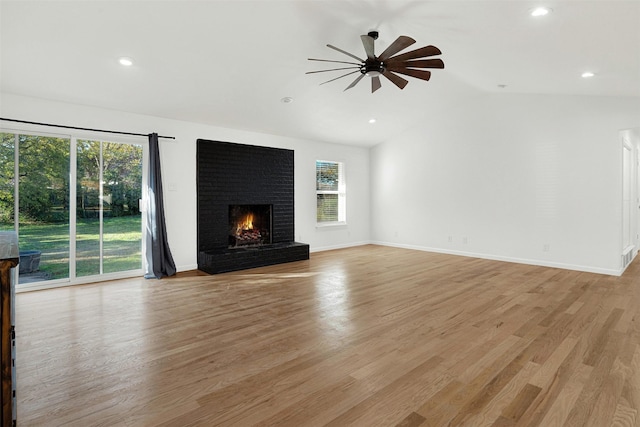 unfurnished living room featuring a brick fireplace, light wood-type flooring, vaulted ceiling, and ceiling fan