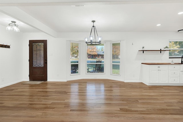 unfurnished dining area featuring a chandelier, light wood-type flooring, and a wealth of natural light