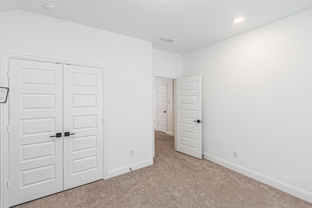 unfurnished bedroom featuring a closet and light carpet