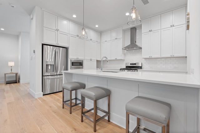 kitchen with appliances with stainless steel finishes, sink, wall chimney range hood, and white cabinets