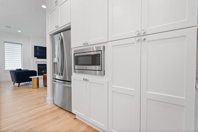 kitchen with white cabinetry, light hardwood / wood-style flooring, and appliances with stainless steel finishes