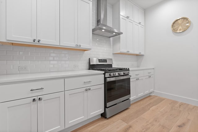 kitchen featuring white cabinetry, stainless steel range with gas stovetop, and wall chimney range hood