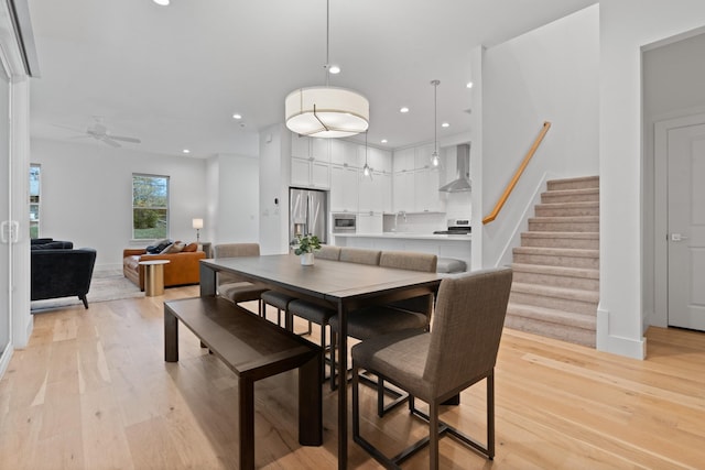 dining area with ceiling fan, sink, and light wood-type flooring