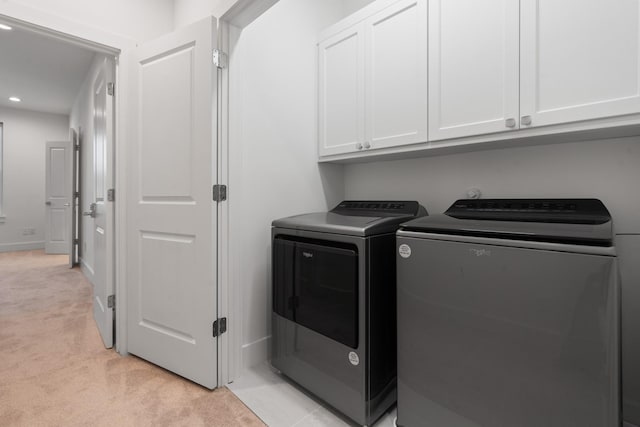 laundry area with cabinets, washer and dryer, and light carpet