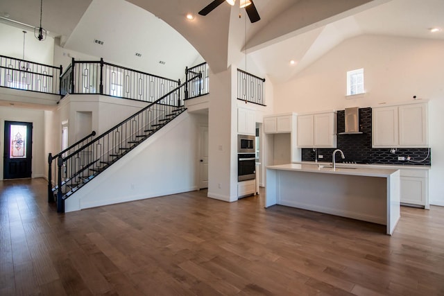 kitchen with stainless steel appliances, high vaulted ceiling, dark hardwood / wood-style floors, and wall chimney range hood