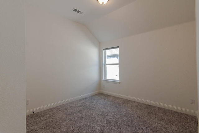 carpeted spare room featuring vaulted ceiling