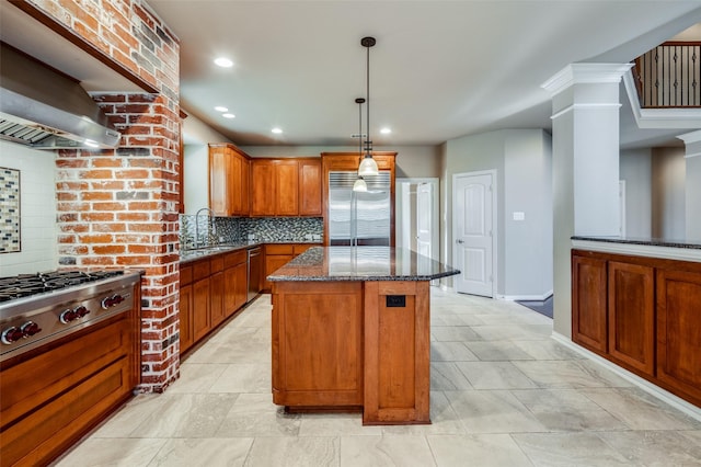 kitchen with a center island, decorative backsplash, sink, appliances with stainless steel finishes, and wall chimney exhaust hood