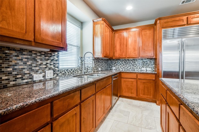 kitchen with decorative backsplash, appliances with stainless steel finishes, sink, and stone counters