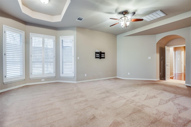 carpeted spare room with ceiling fan and a raised ceiling