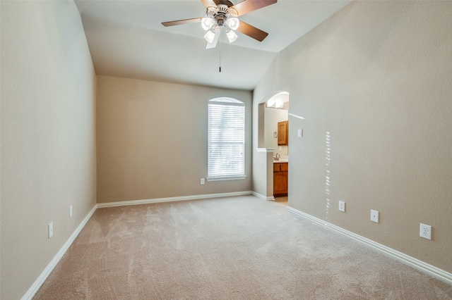 carpeted spare room with ceiling fan and vaulted ceiling