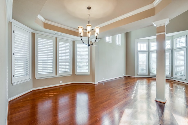 empty room featuring dark wood-type flooring, ornate columns, crown molding, and a tray ceiling