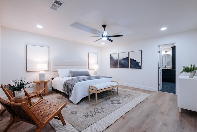 bedroom with ensuite bath, ceiling fan, and light hardwood / wood-style floors