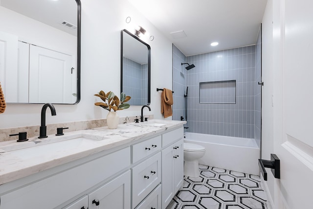 full bathroom with tiled shower / bath, vanity, and toilet