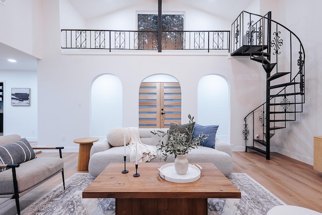 living room with high vaulted ceiling, light wood-type flooring, and french doors