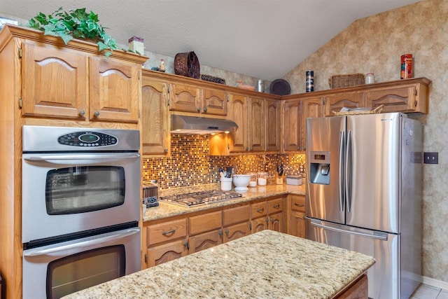 kitchen with backsplash, light stone countertops, lofted ceiling, and stainless steel appliances