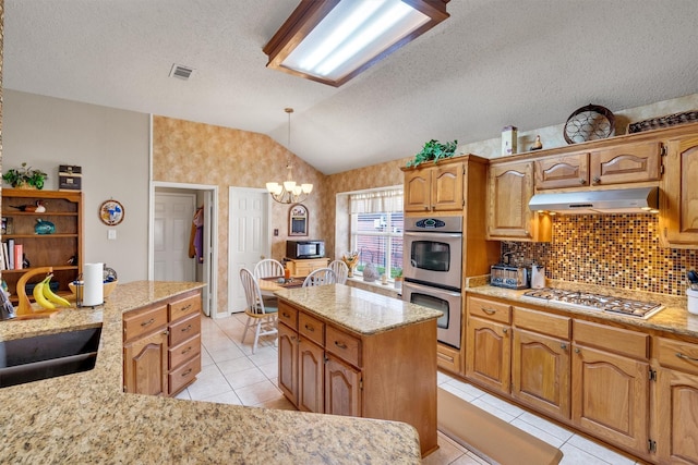 kitchen with sink, a chandelier, lofted ceiling, a kitchen island, and appliances with stainless steel finishes