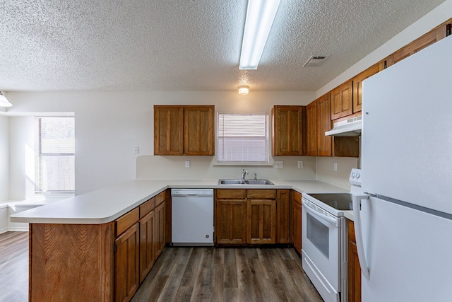 kitchen with white appliances, sink, a textured ceiling, dark hardwood / wood-style flooring, and kitchen peninsula