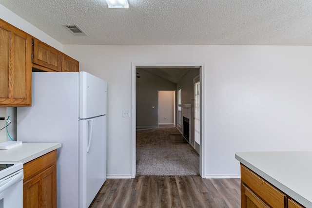 kitchen with white appliances, dark wood-type flooring, and a textured ceiling