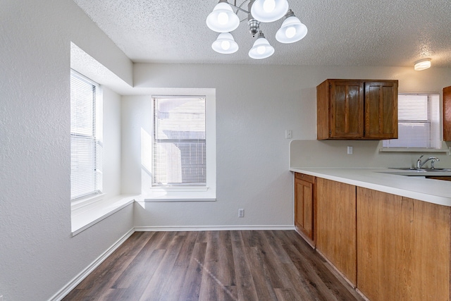 kitchen with a textured ceiling, dark hardwood / wood-style flooring, sink, and a chandelier