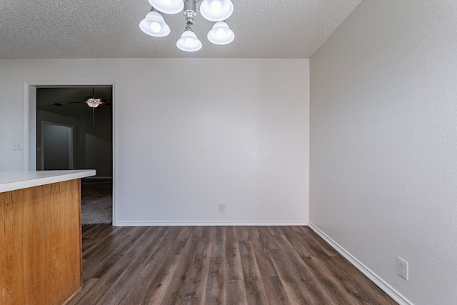 spare room with a textured ceiling, a chandelier, and dark hardwood / wood-style floors