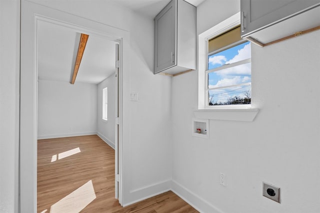 washroom with electric dryer hookup, hookup for a washing machine, light hardwood / wood-style flooring, and cabinets