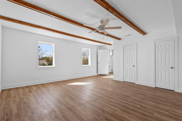 interior space featuring wood-type flooring, ceiling fan, multiple closets, and beam ceiling