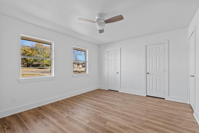 unfurnished bedroom featuring light wood-type flooring, two closets, and ceiling fan