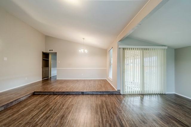 spare room with a notable chandelier, dark hardwood / wood-style flooring, and vaulted ceiling