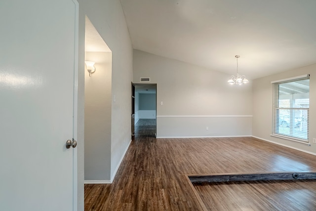 spare room with dark wood-type flooring, lofted ceiling, and an inviting chandelier