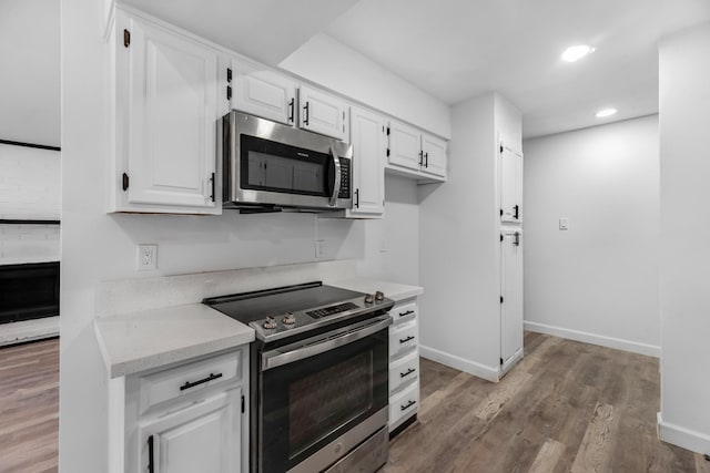 kitchen with white cabinets, appliances with stainless steel finishes, and hardwood / wood-style floors