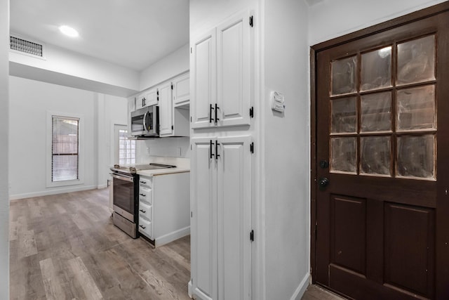 kitchen featuring visible vents, appliances with stainless steel finishes, light countertops, light wood-style floors, and white cabinetry