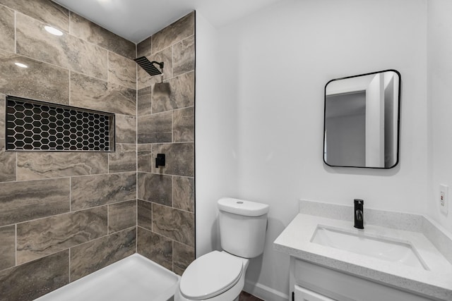 bathroom featuring vanity, toilet, and tiled shower