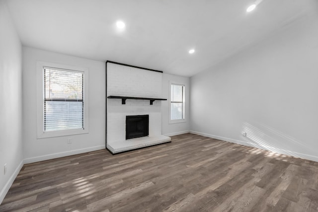 unfurnished living room featuring hardwood / wood-style floors and a brick fireplace