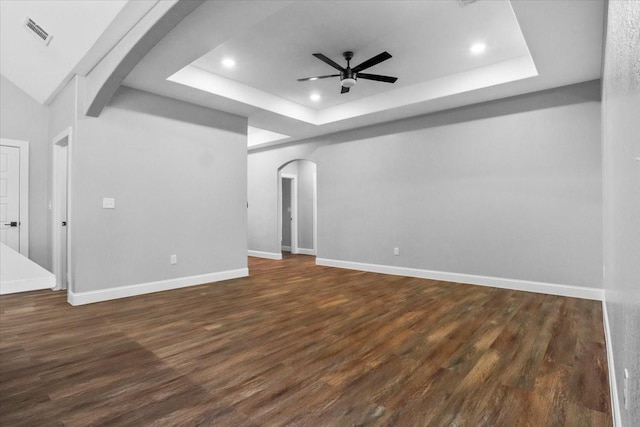 unfurnished living room with dark hardwood / wood-style floors, ceiling fan, and a tray ceiling