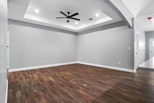 unfurnished room featuring a raised ceiling, ceiling fan, and dark hardwood / wood-style flooring