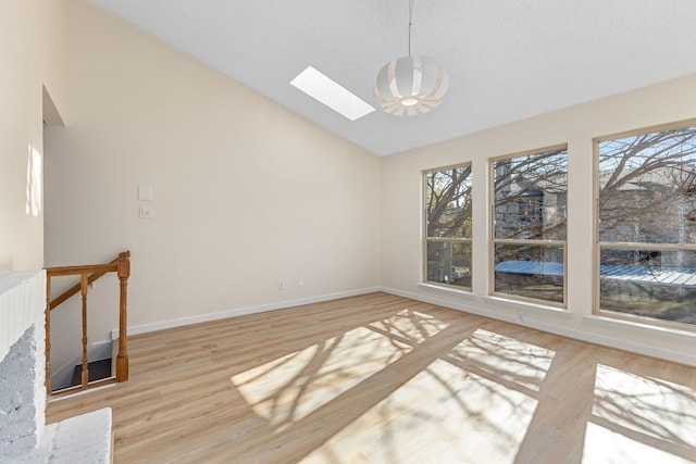 interior space featuring high vaulted ceiling, a skylight, and light hardwood / wood-style flooring