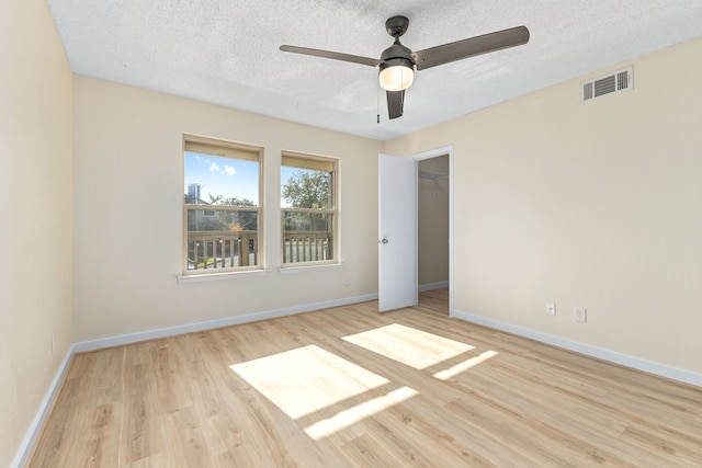 unfurnished bedroom with a textured ceiling, baseboards, visible vents, and light wood-style floors