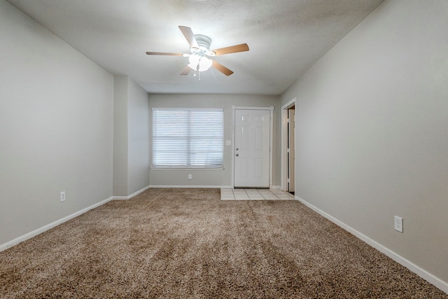 spare room featuring ceiling fan, light colored carpet, and a textured ceiling