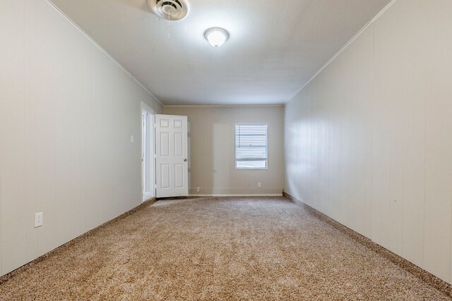 empty room featuring crown molding and carpet