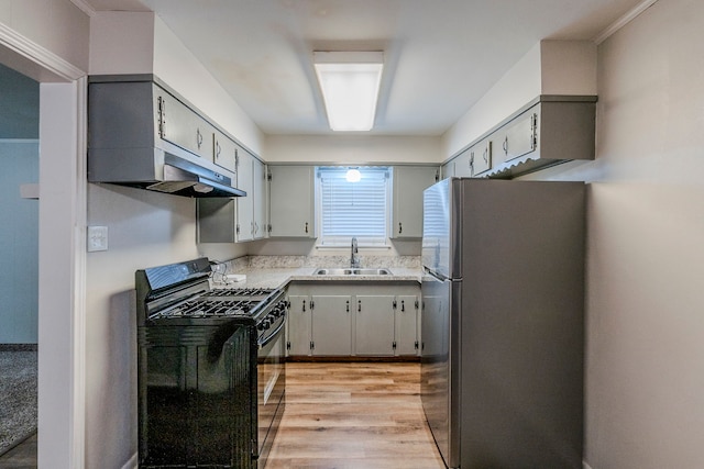 kitchen featuring gray cabinetry, black gas stove, sink, light wood-type flooring, and stainless steel refrigerator