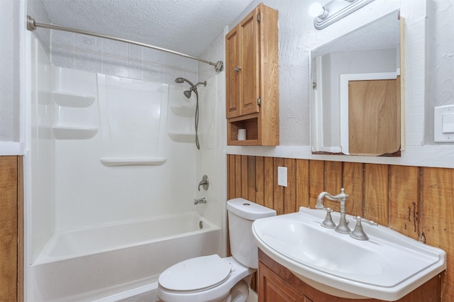 full bathroom with a textured ceiling, toilet, wooden walls, vanity, and tiled shower / bath