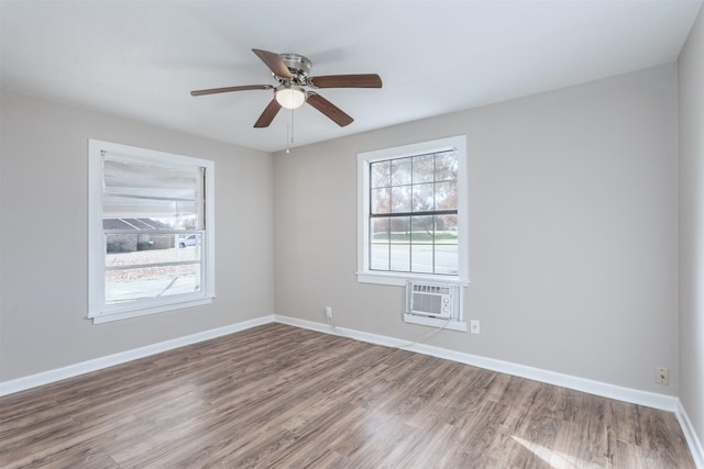 unfurnished room with a wall mounted AC, a wealth of natural light, ceiling fan, and hardwood / wood-style flooring