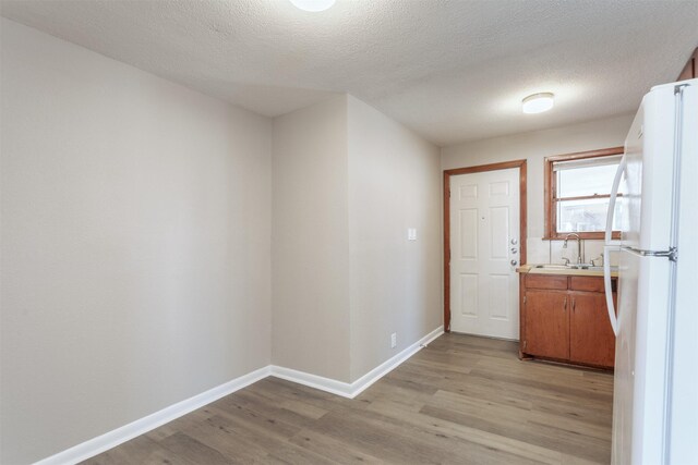 hallway with light hardwood / wood-style floors, sink, and a textured ceiling