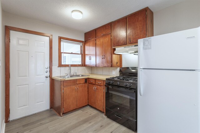 kitchen featuring sink, black range with gas stovetop, light hardwood / wood-style flooring, white refrigerator, and a textured ceiling