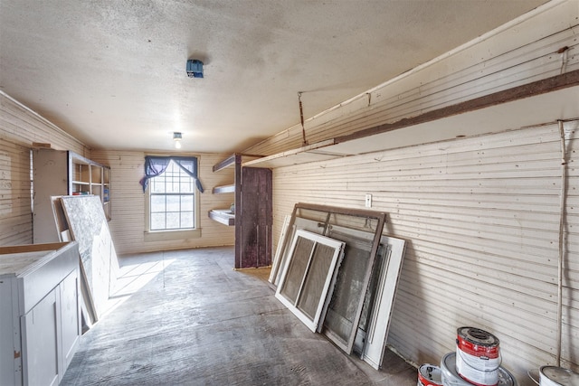 interior space featuring wood-type flooring, wooden walls, and a textured ceiling