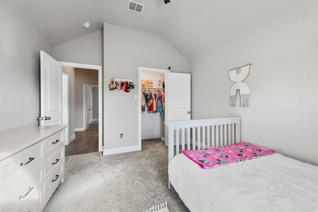 bedroom featuring a spacious closet, a closet, light colored carpet, and lofted ceiling